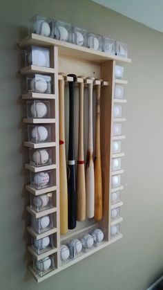 a wall mounted baseball bat rack with many different bats in plastic bins on it