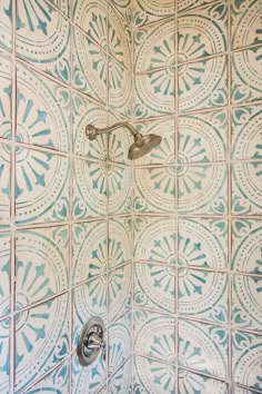 a shower head and hand held faucet in a tiled bathroom with blue and white tiles