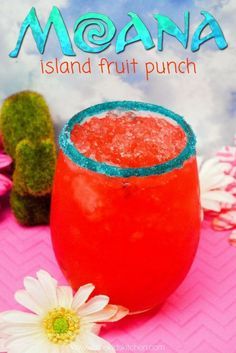 a red drink sitting on top of a pink table next to a cactus and flowers