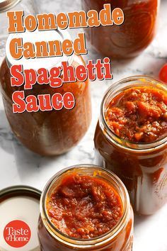 two jars of homemade canned spaghetti sauce on a marble countertop with tomatoes in the background