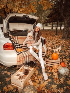 a woman sitting in the trunk of a car with her baby