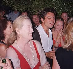 a group of people standing next to each other in front of a tree at a party