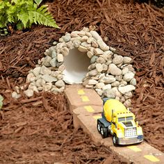 a toy truck is driving through a tunnel made out of rocks and wood mulchs