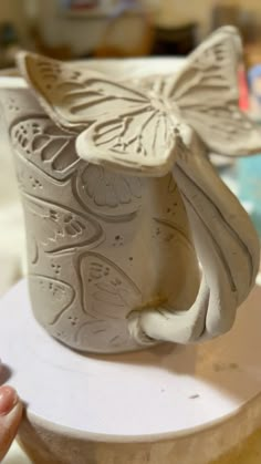 a white ceramic cup with a butterfly on it