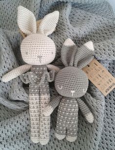 two crocheted stuffed animals sitting on top of a blanket with a tag attached to it