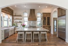 a kitchen with white counter tops and stools next to an island in the middle