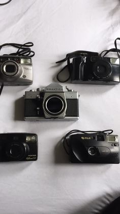 four cameras sitting next to each other on a bed