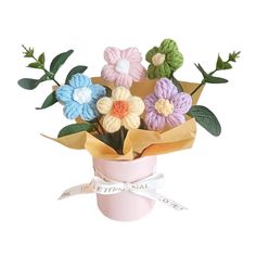 a bouquet of crocheted flowers in a pink vase with ribbon tied around it