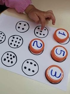 a child's hand pointing at buttons on a sheet of paper with the word u in it