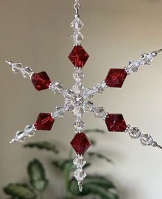 a snowflake ornament with red and clear crystals hanging from it's side