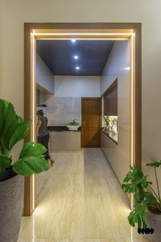 a man is standing in the doorway of a modern house with plants and potted plants