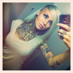 a woman with tattoos taking a selfie in front of a mirror while holding a cell phone