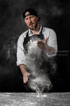 a man in an apron is throwing water into the air with his hands and fingers