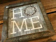 a wooden sign that says home hanging from the side of a building with a wreath on it