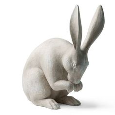 a statue of a white rabbit sitting on its hind legs and looking at the ground