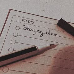 a notepad with the words to do, staying alive written on it next to a pen