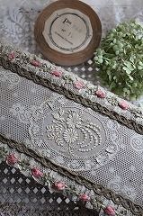 the lace is laying on top of the doily next to some flowers and a wooden bowl