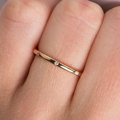 a woman's hand wearing a gold ring with diamonds on the middle of it