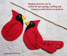 two red birds sitting next to each other on top of a white cloth covered table