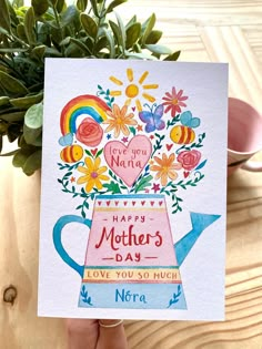 a hand holding up a mothers day card with flowers and hearts in the vase on it