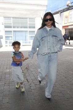 a woman and child walking down a brick road holding each other's hands as they both walk towards the camera