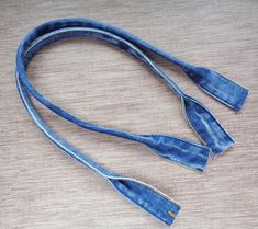 an old pair of blue jeans tied up on a wooden table with the strap still attached