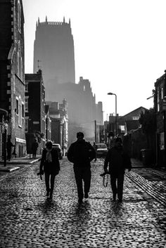 black and white photograph of people walking on cobblestone street