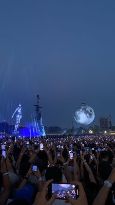 a large group of people taking pictures with their cell phones in front of the stage