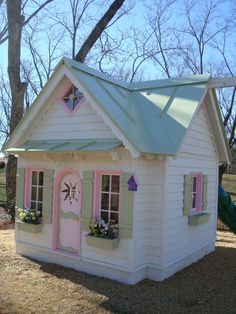 a small white house with pink trim and windows on the front door is decorated in pastel colors