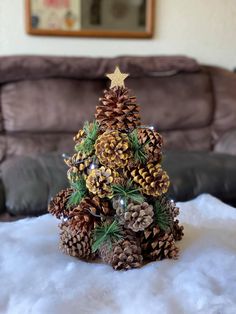 a pine cone christmas tree sitting on top of a snow covered table next to a couch