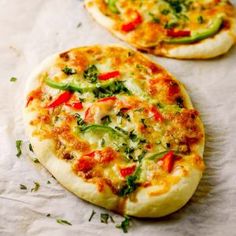 two small pizzas sitting on top of a piece of paper next to each other