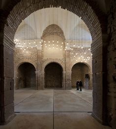 two people are standing in the middle of an empty room with lights hanging from the ceiling