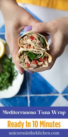 a hand holding a wrap filled with tuna and spinach