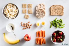 an assortment of food is displayed on a white surface, including crackers, fruit, and cereal