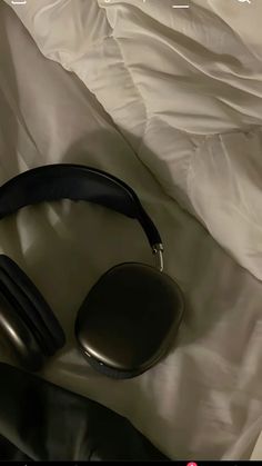 headphones laying on top of a bed next to a white comforter and sheets