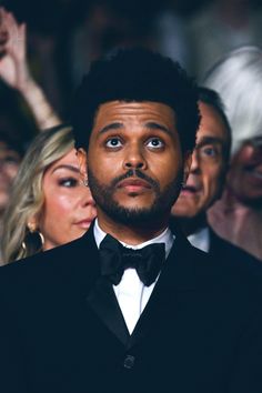 a man in a tuxedo looks up at the camera while others look on