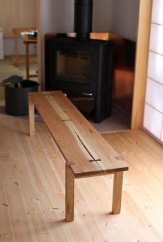 a wooden bench sitting on top of a hard wood floor next to a fire place