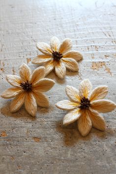 three yellow flowers sitting on top of a wooden table