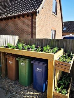 a wooden planter filled with lots of plants next to a fenced in area