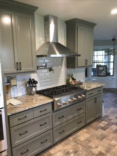 a kitchen with gray cabinets and marble counter tops