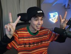 a young man making the peace sign in front of a microphone with his hands up