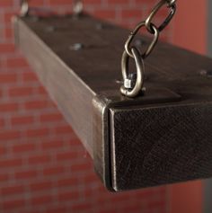 a close up of a metal object on a chain attached to a brick wall with red tiles in the background