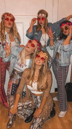 four girls in hippie outfits posing for the camera with their hands up and one girl wearing red sunglasses