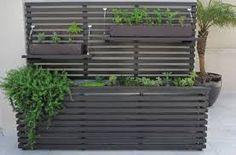 an outdoor planter with plants growing in it and on the side of a building