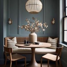 a table with chairs and a vase on it in front of a window next to a bench