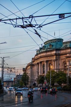 cars are driving down the street in front of a large building with a dome on top