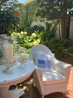 two white wicker chairs sitting next to each other on top of a brick patio