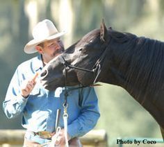 a man standing next to a black horse