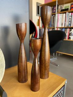 three wooden vases sitting on top of a table in front of a book shelf