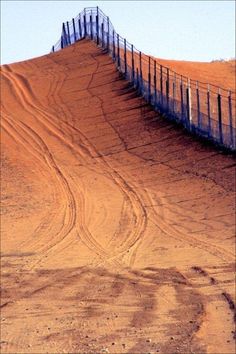 a wooden fence on top of a sandy hill